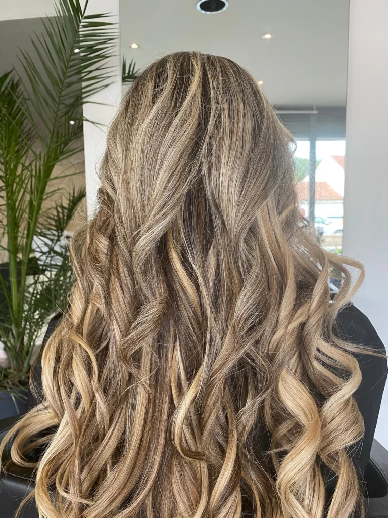 Balayage blond beige sur cheveux longs ondulés dans notre salon de coiffure végétal & biologique à Vigneux-sur-Seine